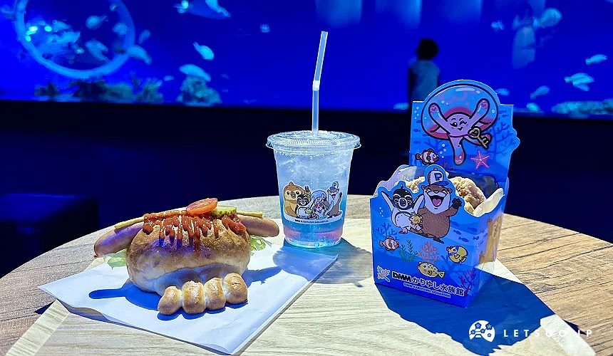 水族館內販售的餐點,一張桌子上面有熱狗堡、果凍氣泡飲、炸雞