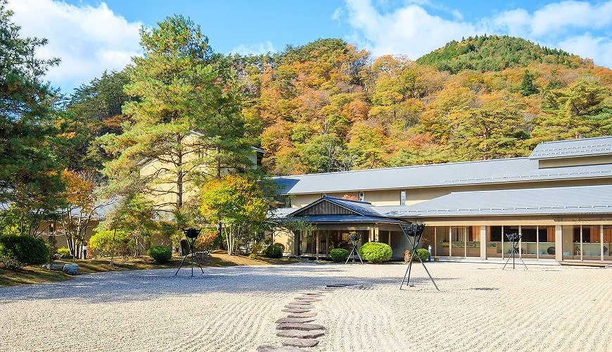 前景為沙地、後方為山坡的日式建築