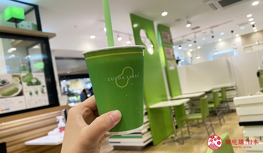 手持毛豆泥奶昔,背景為店內座位