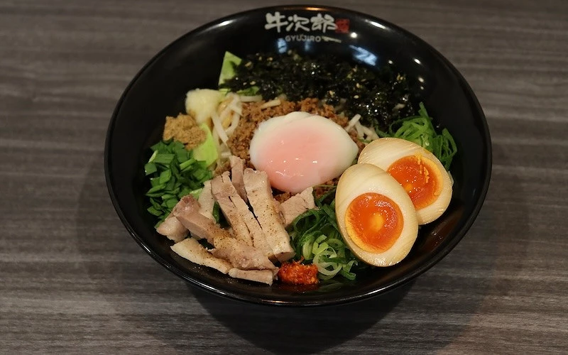 一碗鋪有溫泉蛋、肉燥、叉燒、溏心蛋、韭菜、蔥花、海苔絲的乾拌麵
