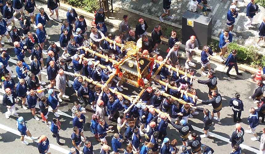 大阪夏日傳統祭典『住吉祭』,參與者扛著神轎在街道上遊行,展現熱鬧祭典氛圍
