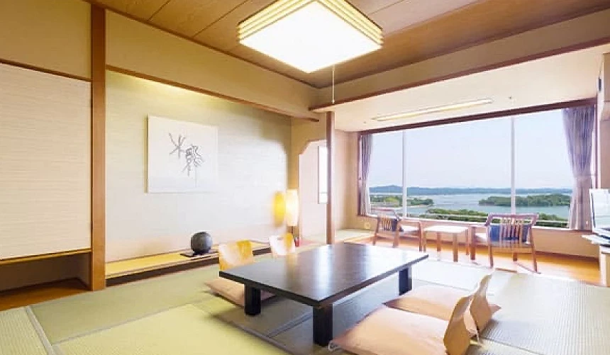 和室房間中央有一張桌子與四張椅子,窗外有海景,窗戶邊有桌椅