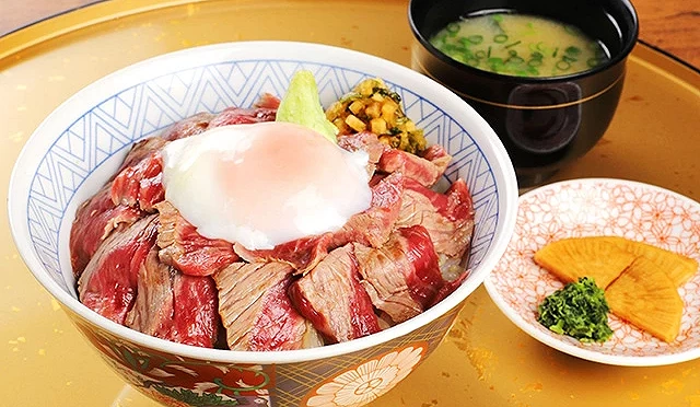 赤牛丼以三分熟的薄切赤牛肉搭配溫泉蛋與醃菜,是阿蘇Hanabishi的招牌美食