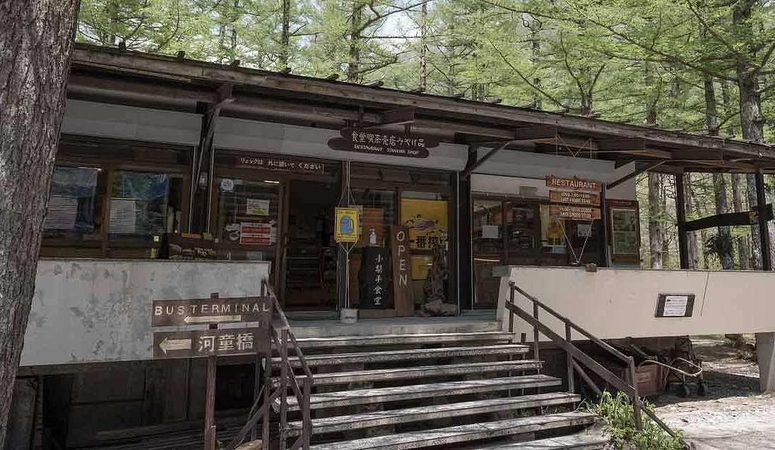 木造屋頂的房子,門口前面有幾階樓梯,後面是一片綠色樹林。
