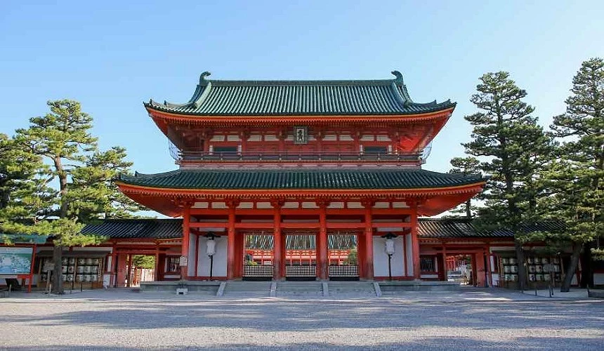 京都平安神宮的大鳥居與應天門,朱紅色柱體與綠瓦屋頂的壯麗建築風格,周圍松樹林立,展現莊嚴與典雅氛圍。