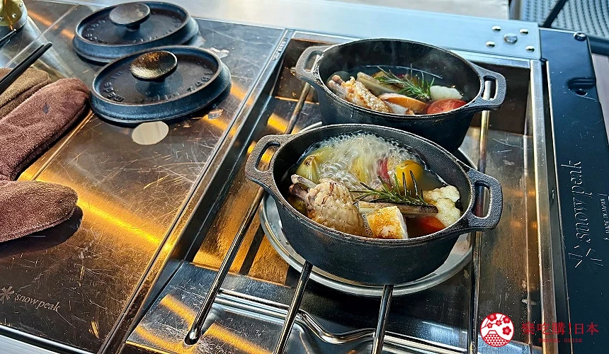 雙口爐上兩個鑄鐵鍋煮著雞肉與蔬菜湯,湯中有迷迭香點綴