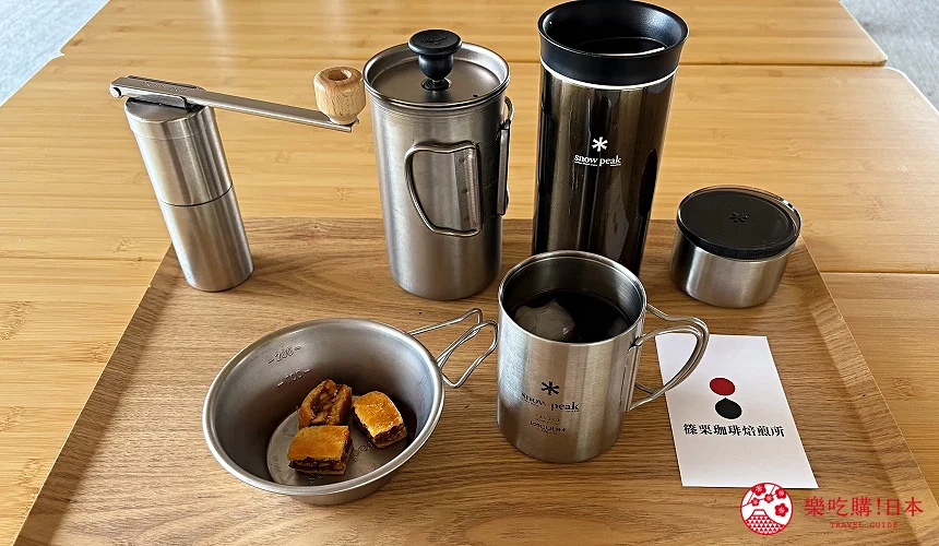 金屬濾壓壺與不鏽鋼杯組合,托盤上有咖啡與小點心