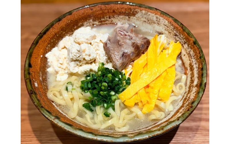 碗中盛有麵條,配料包括豆腐、青蔥、豬軟骨與蛋絲