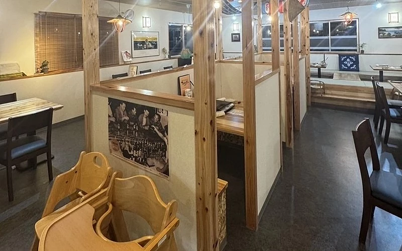 餐廳內部木質隔間座位,前景放有兒童座椅