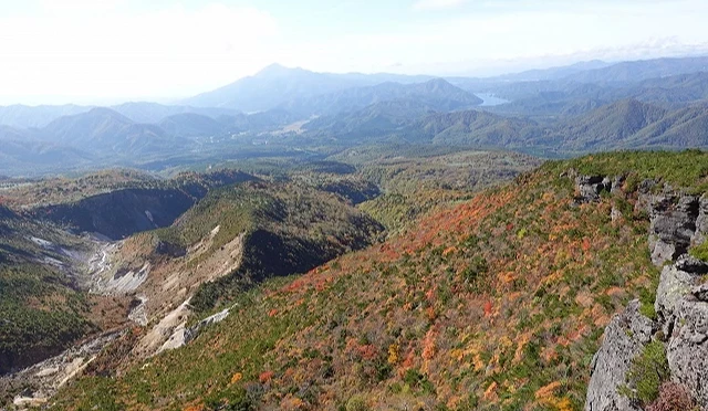 福島縣安達太良山秋日景色,山坡染上紅黃綠交織的楓葉,遠方可眺望連綿群山與湖泊