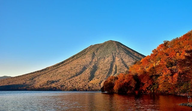 秋天楓紅圍繞的中禪寺湖,遠望橙色的男體山倒映湖面