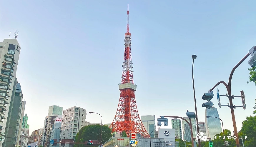 東京鐵塔矗立於市中心,紅白相間的塔身在藍天映襯下顯得格外醒目,周圍高樓林立,展現出都市繁華景象。