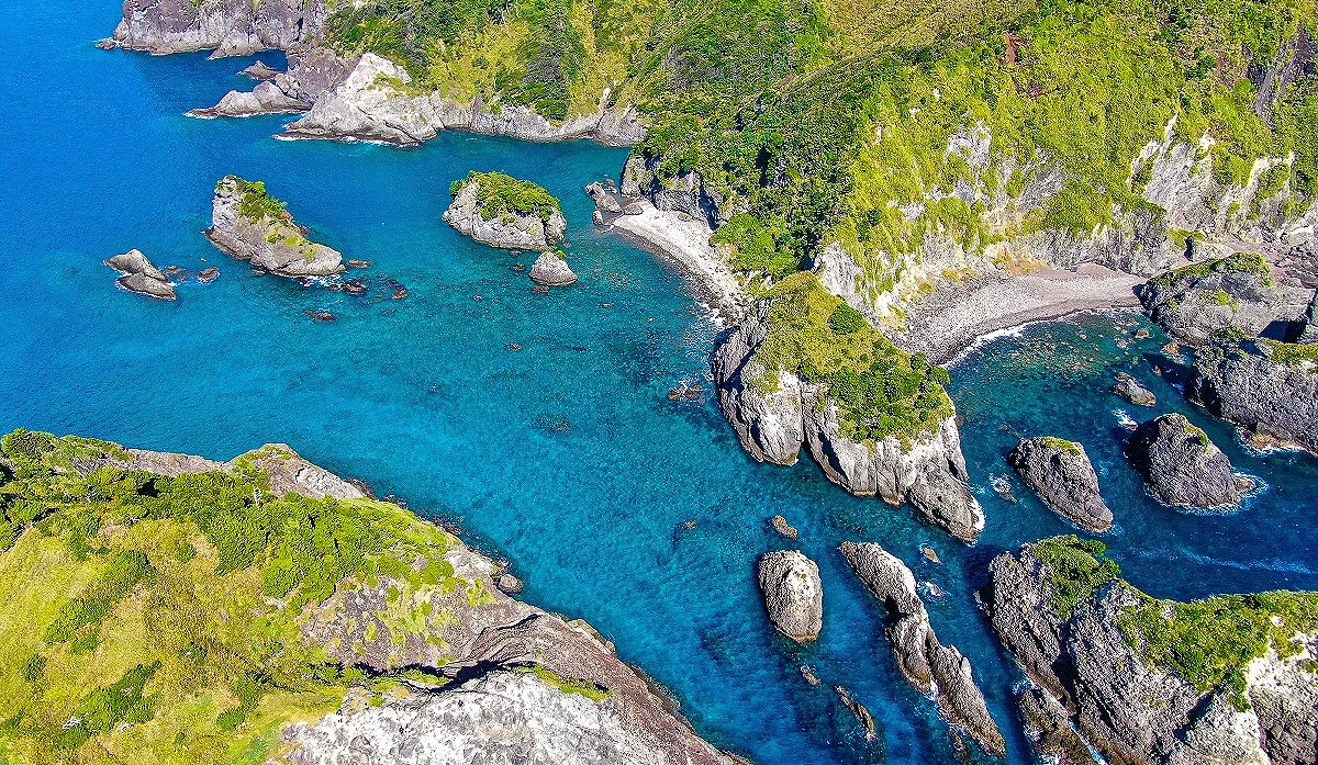 綠色山脈和岩石中間,有藍色海洋