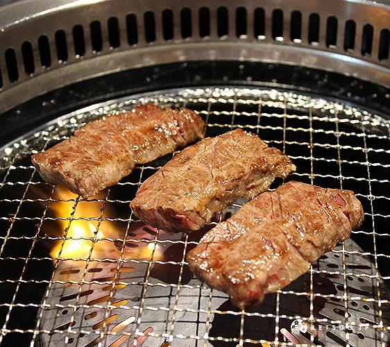 烤網上放著三塊已烤至焦香的和牛肉