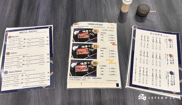 桌上攤放三份菜單,內容有鰻魚飯套餐價格與餐點介紹
