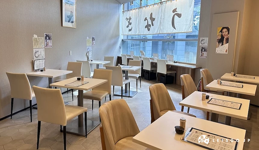 餐廳內部座位區,擺放淺色桌椅,桌上有菜單
