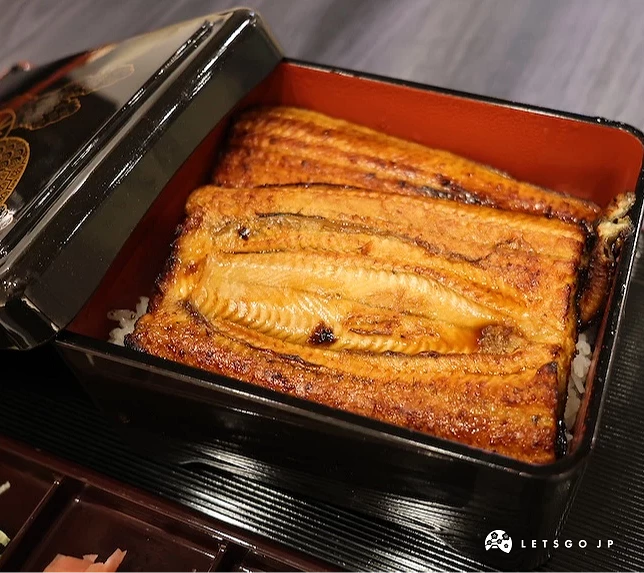 餐盒內盛裝白飯,上方覆蓋兩大片烤鰻魚