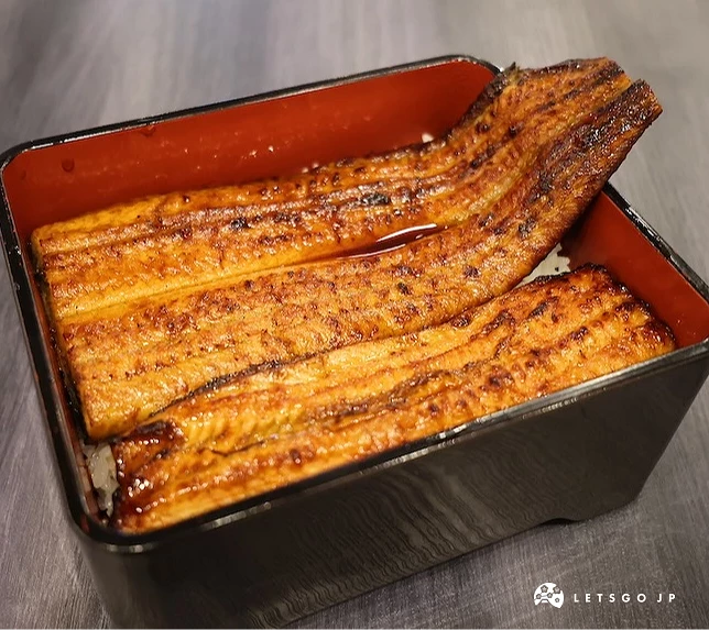 餐盒內白飯上放置兩大片長條烤鰻魚