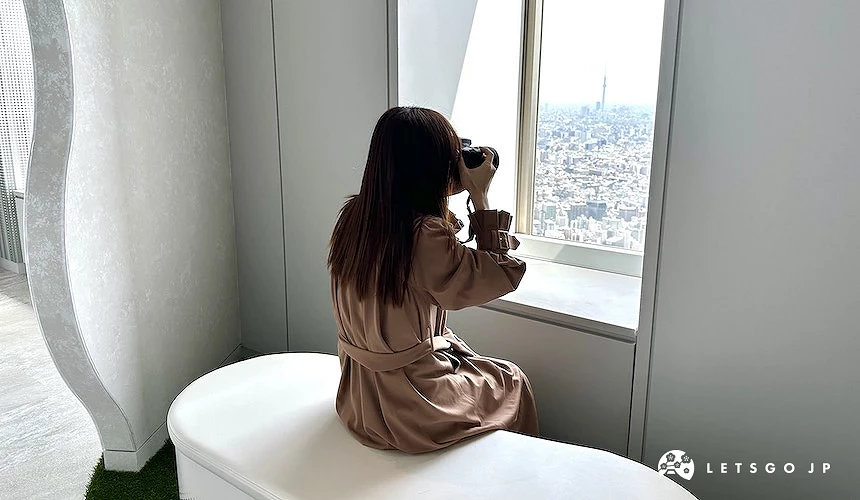 一位女性在窗前拿著相機拍照