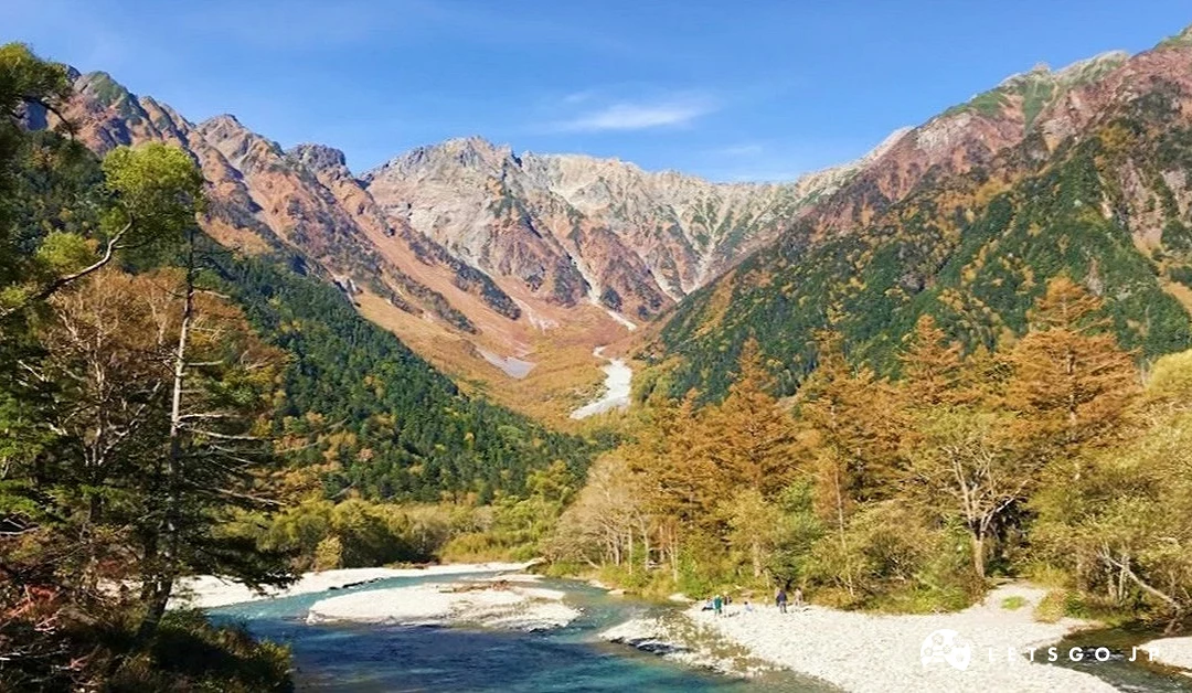 後面有金黃色山脈,前面是綠色樹林跟金黃色樹林,中間有一條溪流