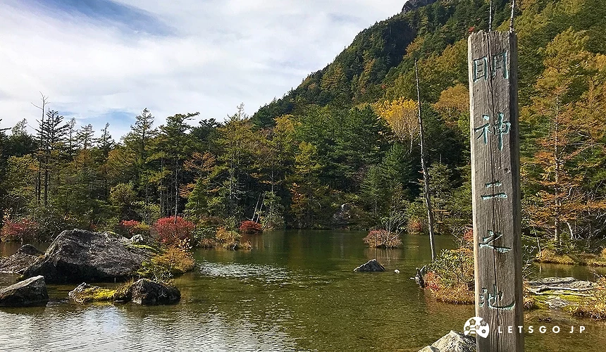 後面是黃綠色樹林,前面有一面糊,右側有一個木頭標誌印著「明神二之池」