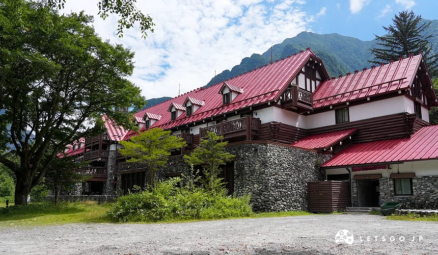 藍天白雲,還有一棟紅色屋頂的建築,左右兩邊有樹林