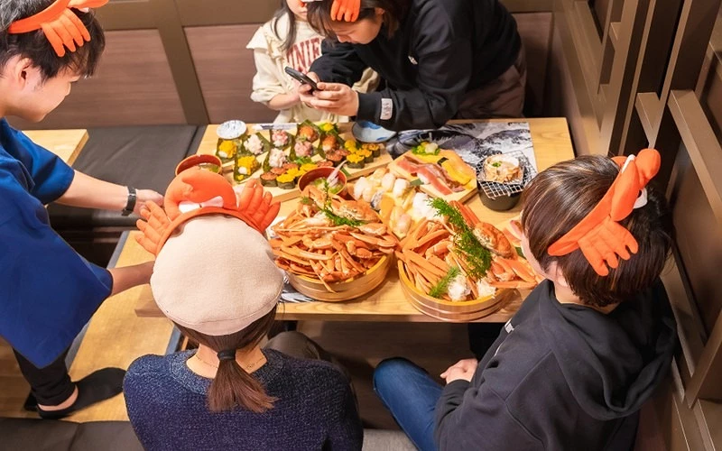 多人圍坐桌旁享用螃蟹與壽司料理