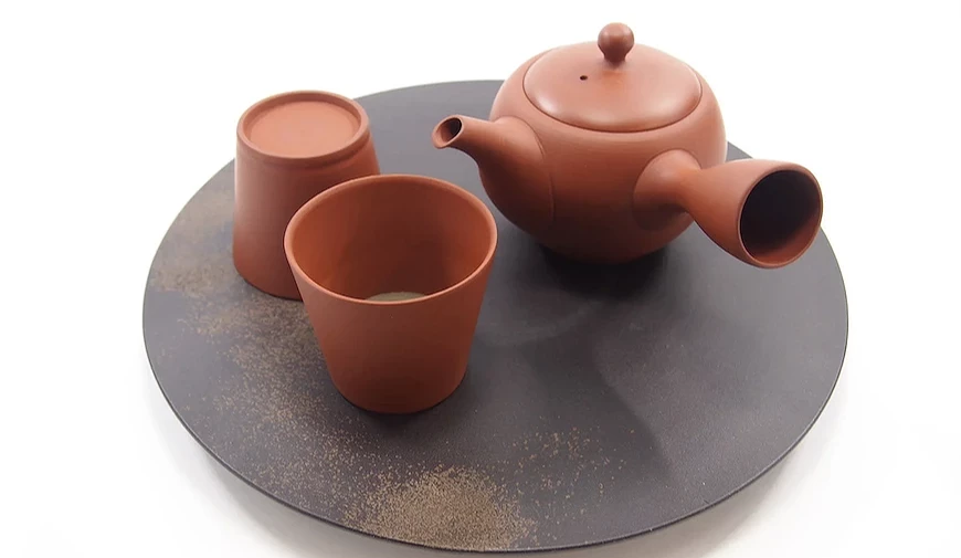 愛知縣的常滑燒,圖為磚紅色扁圓形茶壺與兩個同樣顏色的茶杯