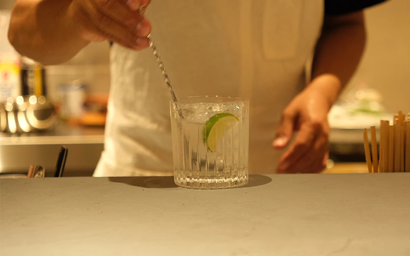 吧檯前有人攪拌放有青檸片的透明飲品