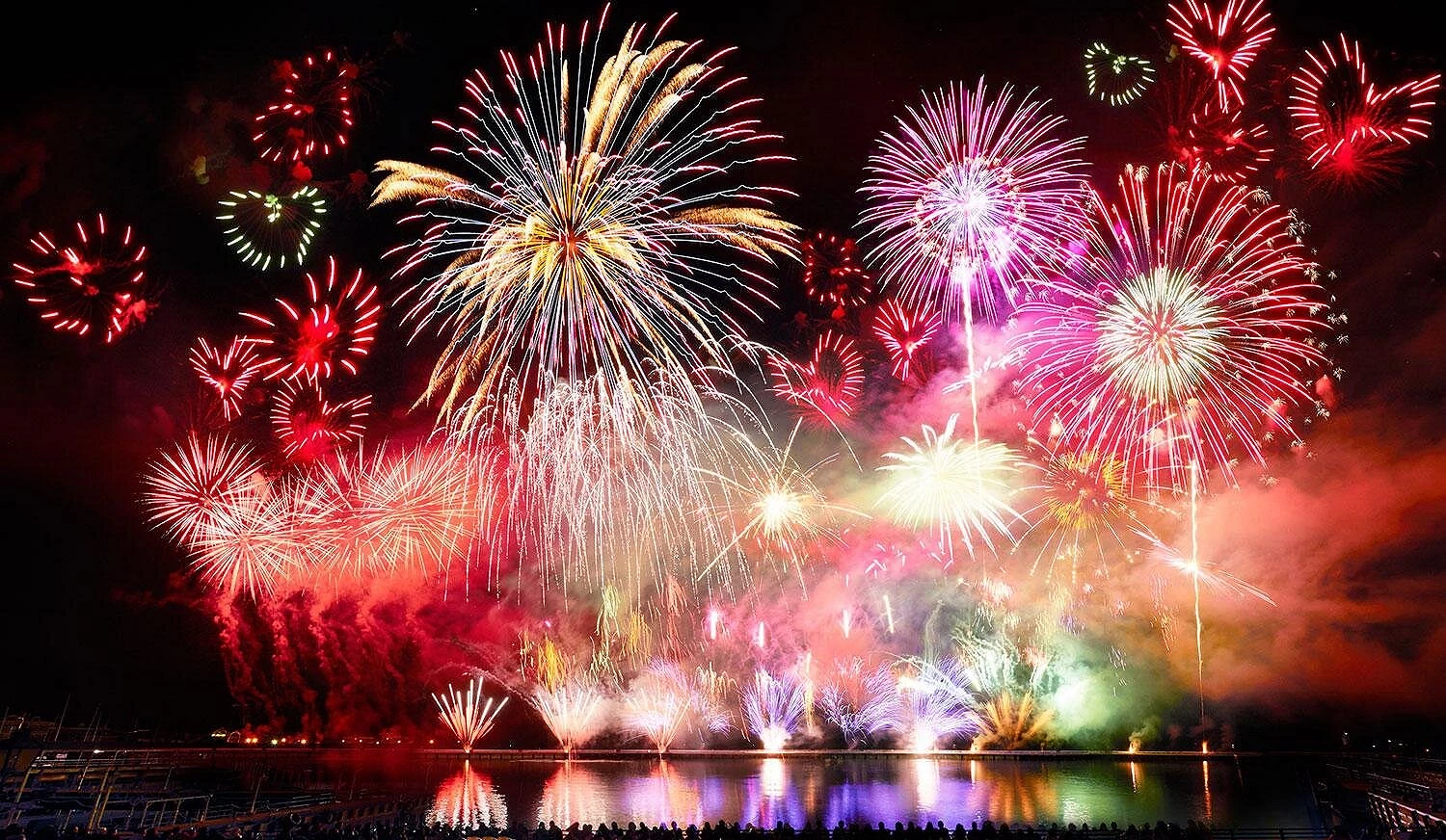 夜空中綻放的多彩煙火照亮水面,觀眾席滿座,豪斯登堡冬季花火表演氣勢磅礴