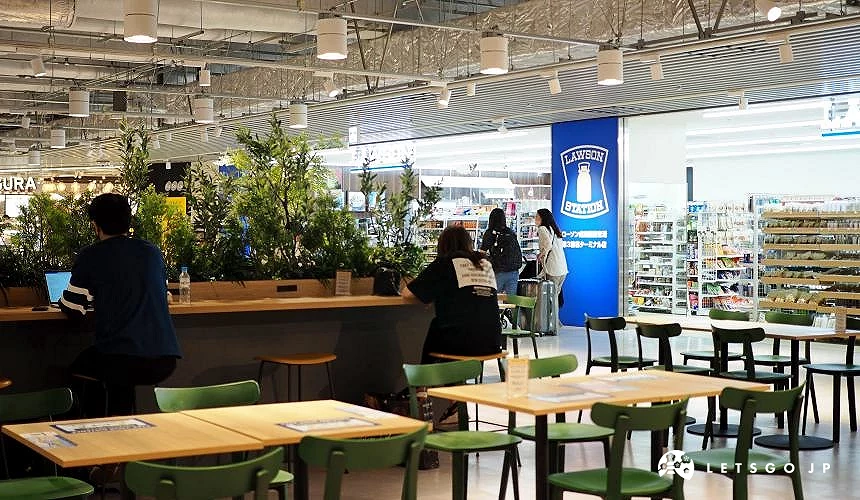 成田機場第三航廈2樓的美食與休憩空間,旅客在桌邊休息或使用筆電,背景為 LAWSON 超商與「Fa-So-La KAGURA」商店入口