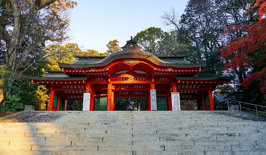 石階上方鮮紅色的神社山門,周圍樹木染上秋色
