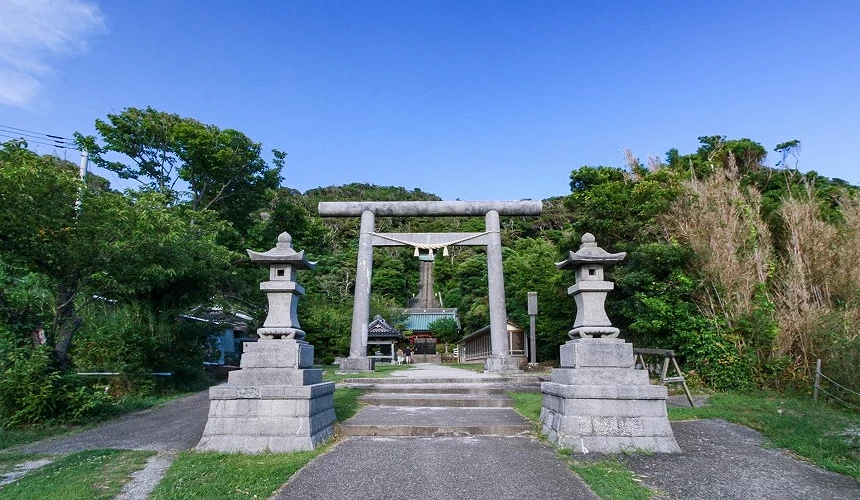 石燈籠與鳥居矗立在神社參道入口,背景是綠意盎然的山林