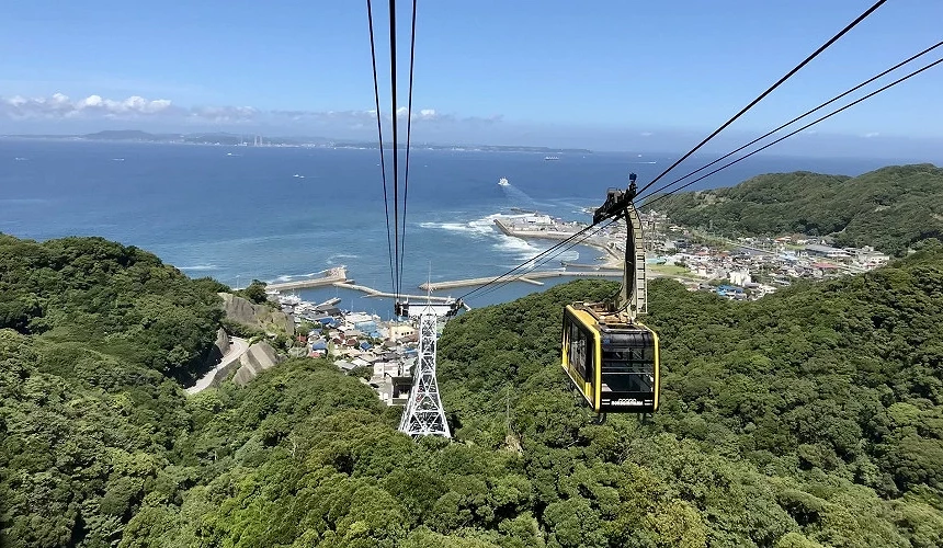 黃色纜車穿越山林高空,遠眺海港與藍色大海景致。
