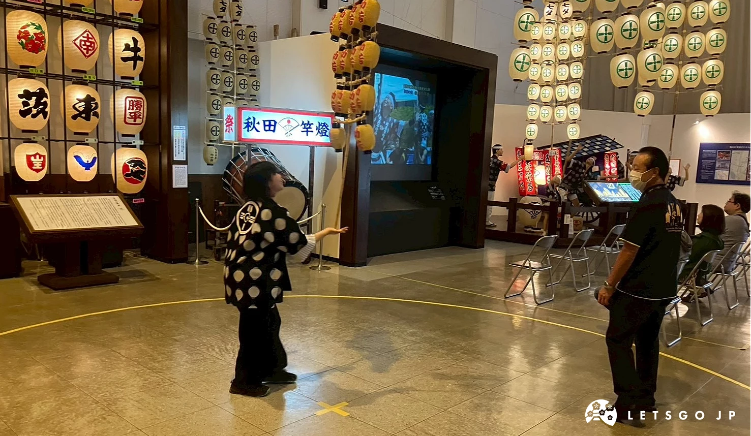 一個人體驗竿燈,旁邊有工作人員