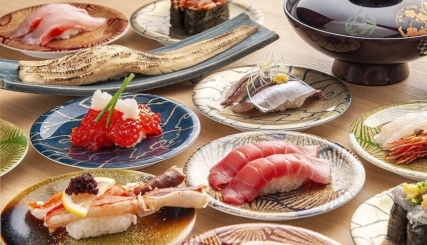 桌上排滿裝了各種料壽司的圓形盤子