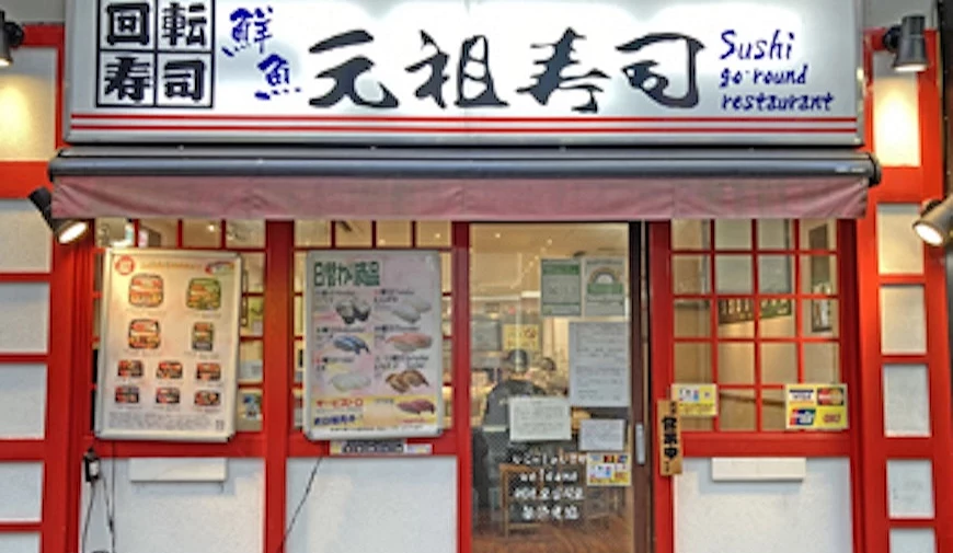 元祖壽司的店面用紅色木框與白色牆壁,白色大大的招牌寫著黑色書法字
