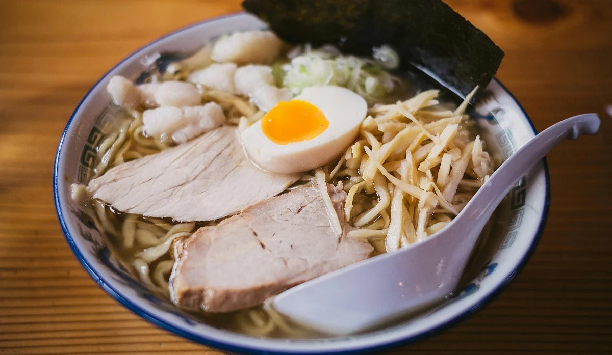 一碗熱騰騰的日式拉麵特寫,配料包括叉燒肉片、糖心蛋、筍乾、海苔和蔥花。
