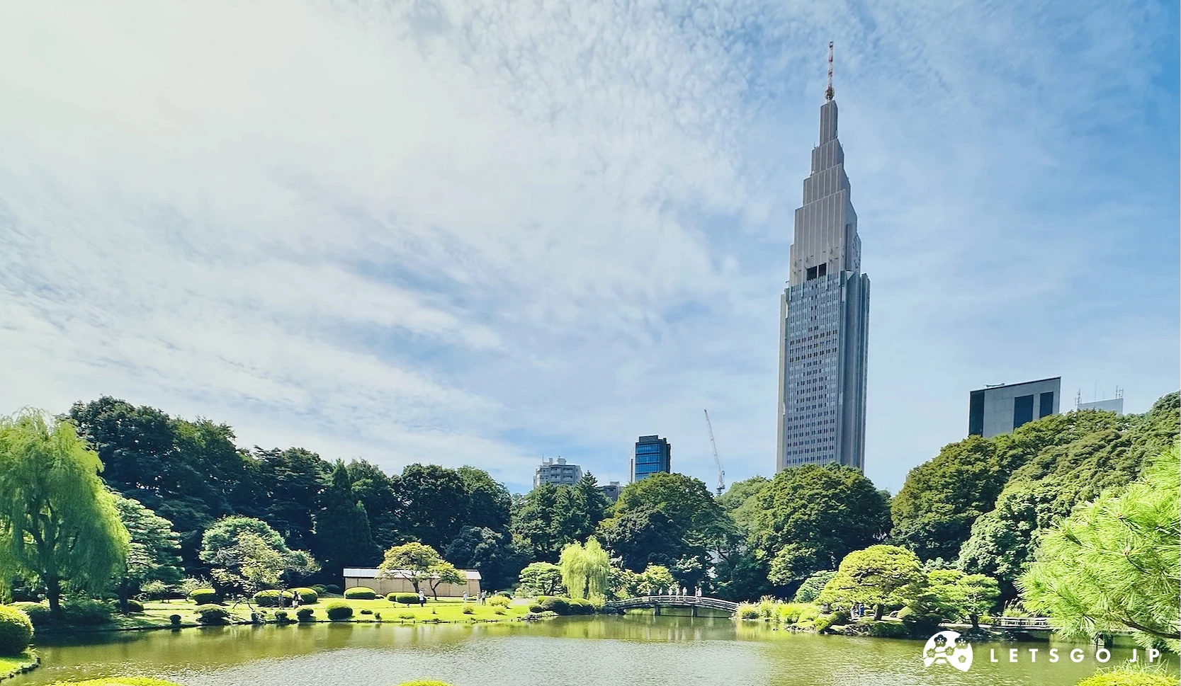 新宿御苑內的上之池,遠處有一整排的樹木,最後有一棟高聳的高樓
