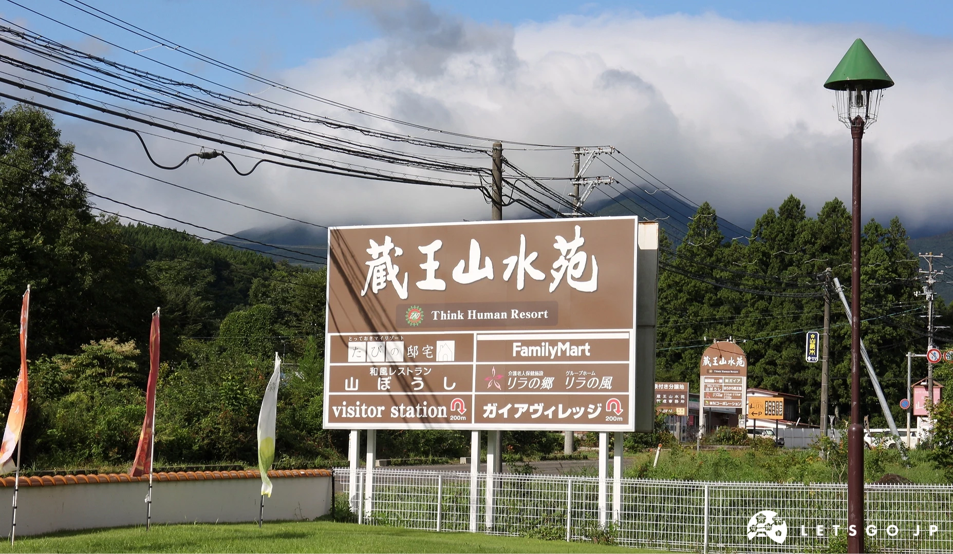 寫有「藏王山水苑」與「FamilyMart」等店名的棕色招牌,背景為樹林與雲霧山景