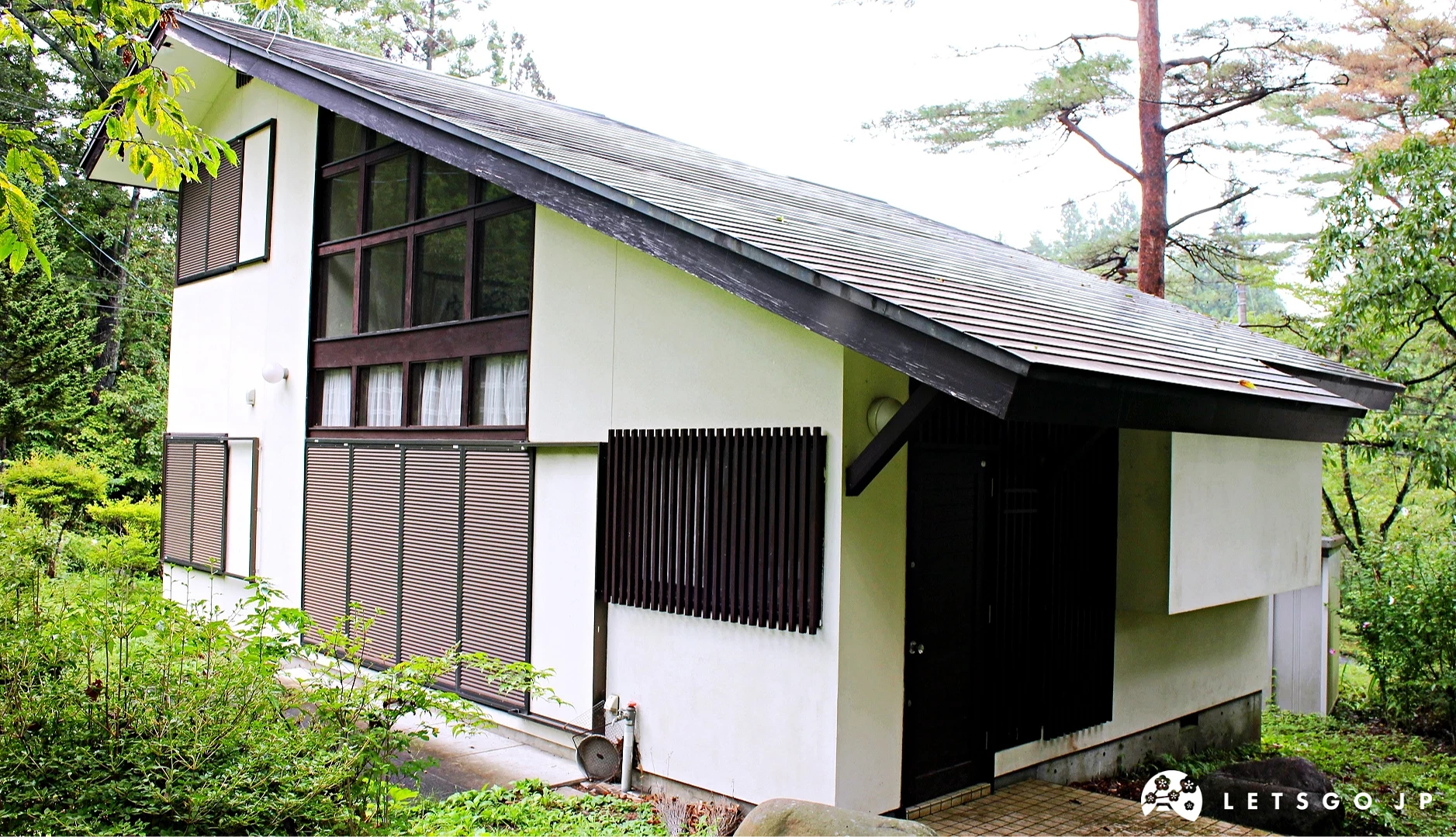 被綠樹包圍的白色斜屋頂木造住宅外觀