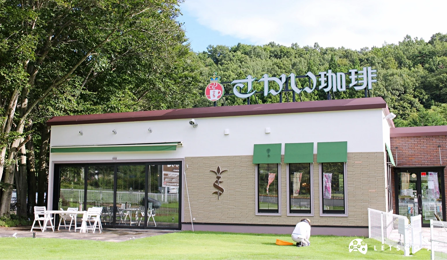 寫有「さかい珈琲」的咖啡館外觀,白色牆面搭配綠色遮陽板,前方有草坪