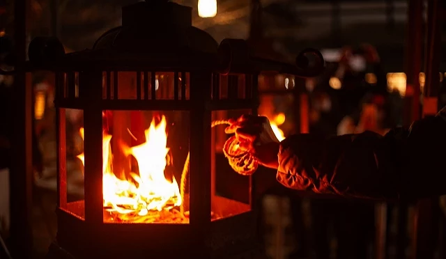 夜間的神社境內,民眾將繩子靠近燈籠內的火焰點燃