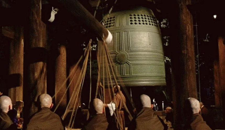 多名僧侶合力拉動粗繩敲擊知恩院巨大的梵鐘,於夜間進行除夜之鐘儀式的場景