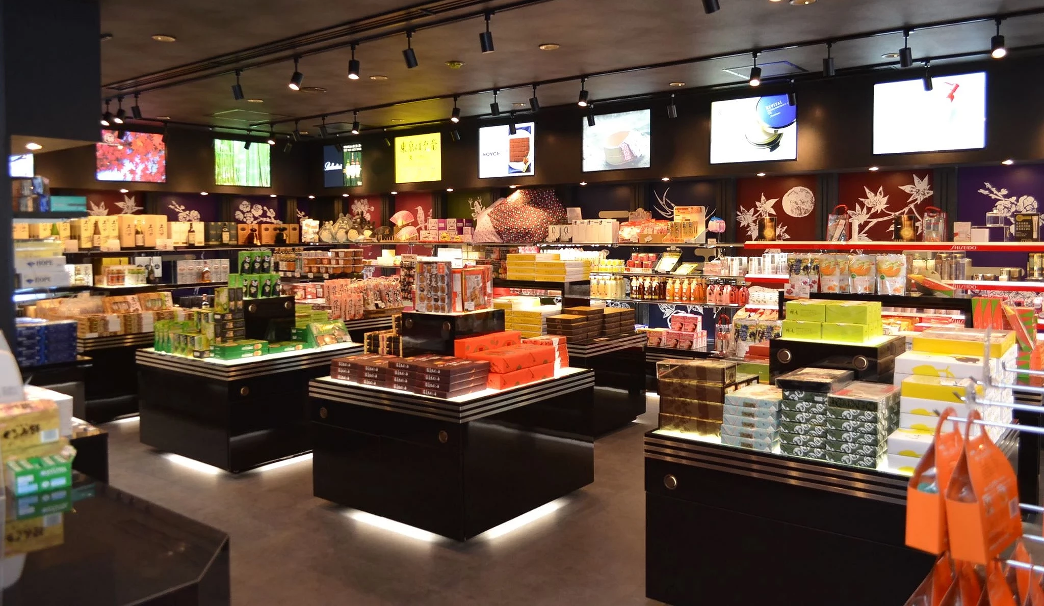 大分機場國際線免稅店內部陳列景象,多種日本零食、伴手禮、酒類與化妝品整齊擺放在展示台上,燈光明亮、空間寬敞