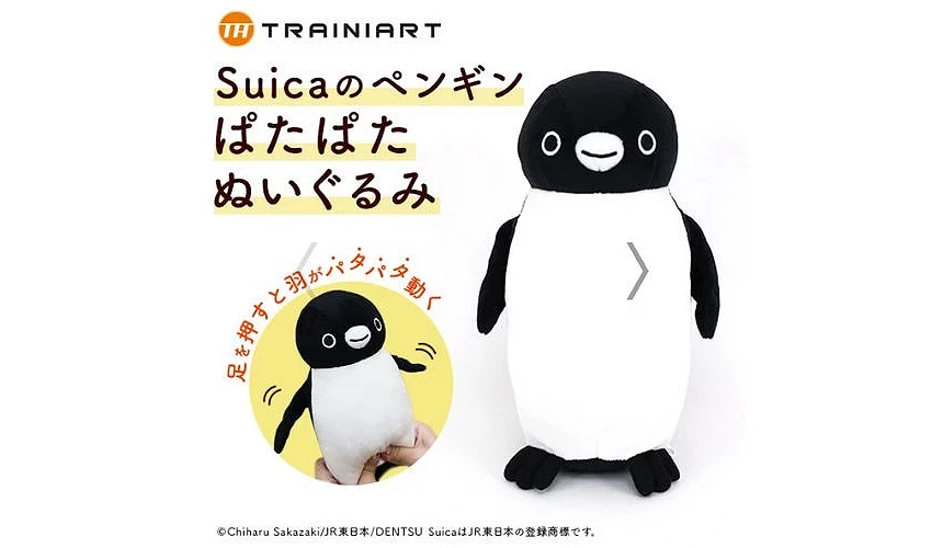 一隻黑白配色的 Suica 企鵝玩偶,按壓腹部時雙翼會揮動,並附示意圖展示拍動動作