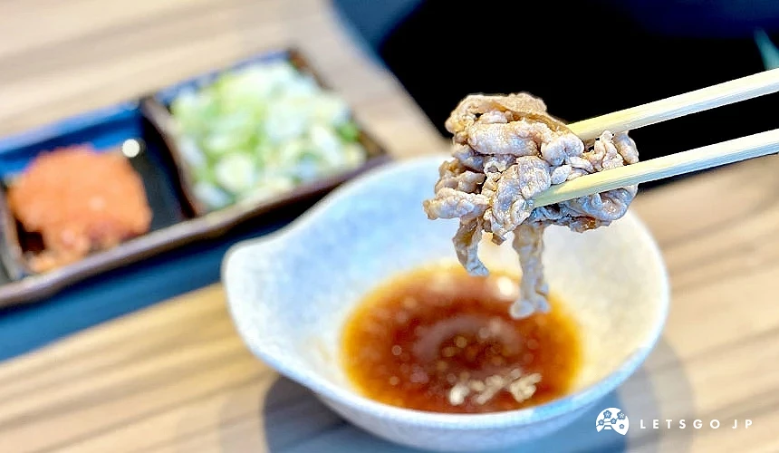 用筷子夾著肉片,下方有沾醬