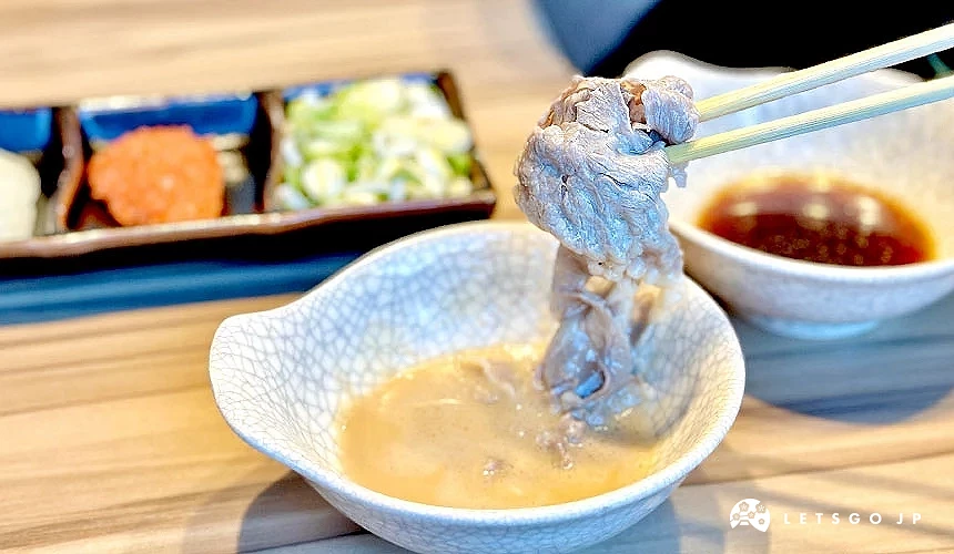用筷子夾著肉片沾胡麻醬