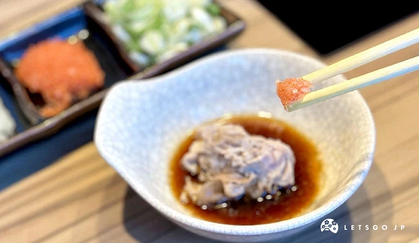 用筷子夾著紅蘿蔔泥,下方是放在醬汁裡的肉片