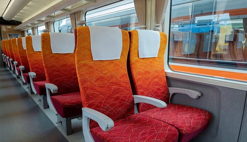 新幹線普通車廂座位,橙紅色椅套排列整齊,窗外可見月台景色
